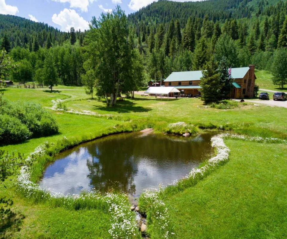 Гірська долина з будиночками та невеликим озером серед зелених пагорбів